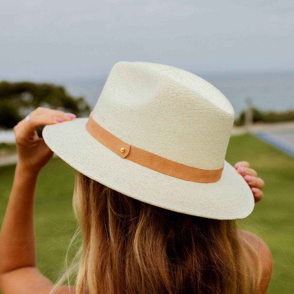 Person wearing a white straw hat with a brown band outdoors